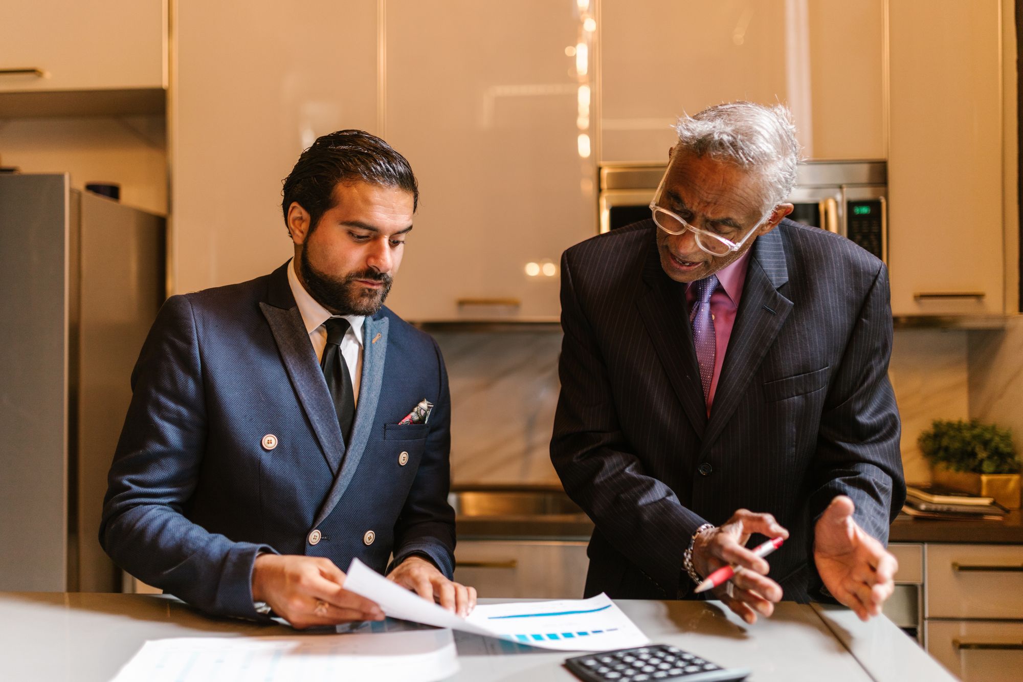 Two people reviewing a printed investment chart together at a kitchen table in warm daylight